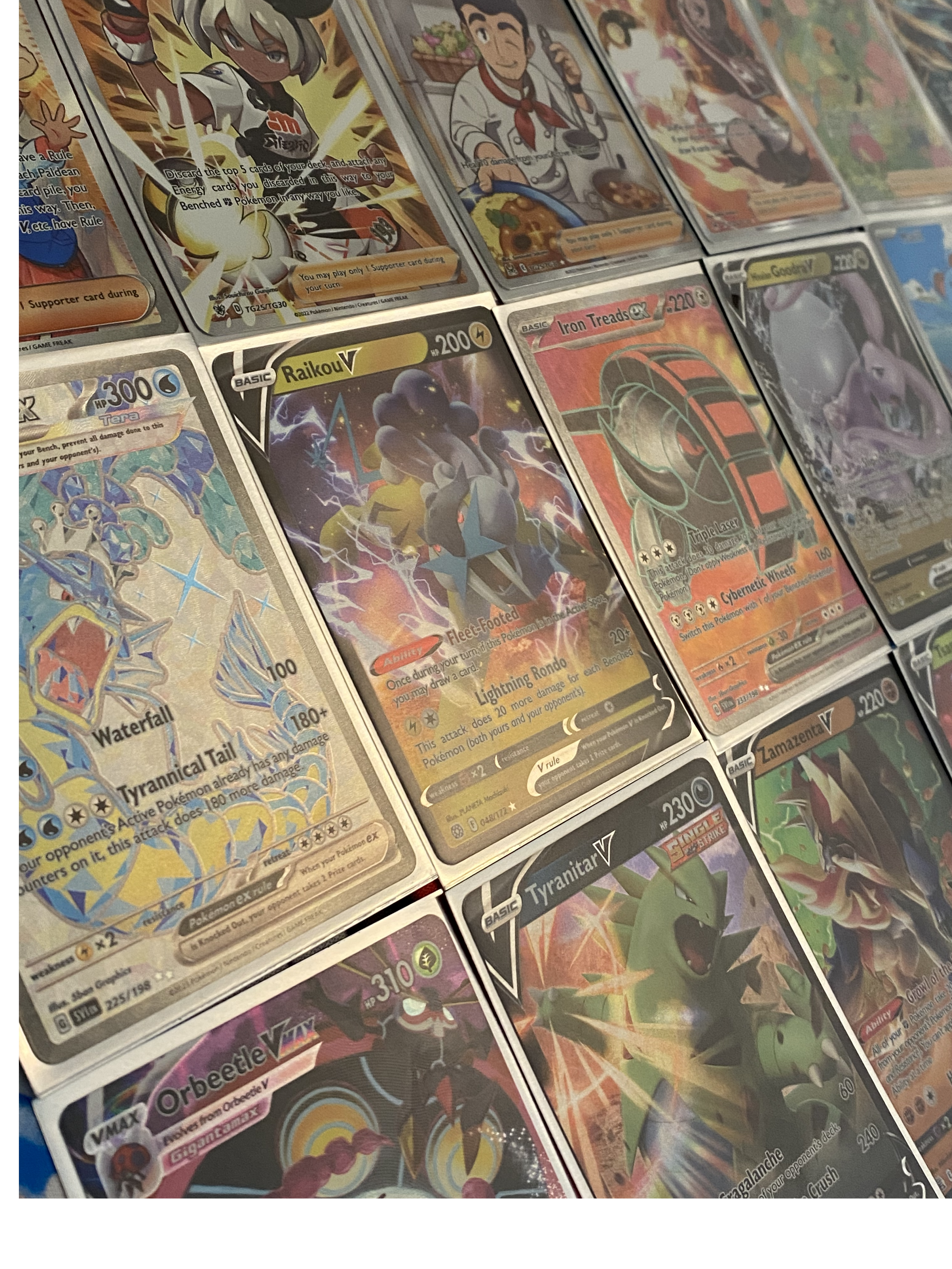 Close-up of assorted Pokémon V and VMAX cards arranged in rows, featuring full-art and holographic designs.